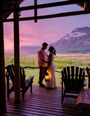 Orta yaşlı bir çift, Güney Afrika 'da tatil yaparken kulübelerinin önünde Hermanus yakınlarındaki Garden Route Western Cape South Africa Sahili' nde dağ ve otlaklar.. 