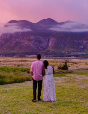 Orta yaşlı bir çift, Güney Afrika 'da tatil yaparken kulübelerinin önünde Hermanus yakınlarındaki Garden Route Western Cape South Africa Sahili' nde dağ ve otlaklar.. 