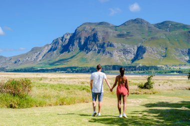 Hermanus yakınlarındaki dağlarda Güney Afrika Balina Burnu 'nun batı yakasında. Güney Afrika 'da tatil yaparken orta yaşlı bir kadınla bir çift kulübelerinin önünde.
