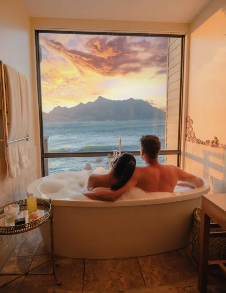 一对夫妇的男人和女人在一个浴缸里看着在开普敦的海面上度假的南非 日落时浴盆 度假时按摩浴缸 — 图库照片