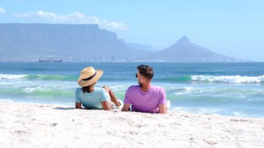 Bloubergstrand Cape Town Güney Afrika 'da güneşli bir yaz gününde, kumsalda bir çift, Cape Town Güney Afrika' da tatilde olan erkekler ve kadınlar