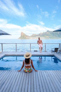 Sonsuzluk Havuzu 'nun önündeki çift, Güney Afrika Burnu okyanusuna bakıyor. Gün batımında bir kadın ve erkek yüzme havuzunda.. 