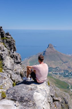 Cape Town Güney Afrika 'daki Masa Dağı manzaralı okyanusa bakan adamlar ve Table Mountain Cape Town' dan Lions Head.