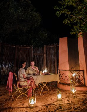 Birkaç erkek ve romantik kadın, Güney Afrika 'da lüks bir safaride yemek yiyorlar. Oyun parkının çalılığında lüks bir safari kulübesi.