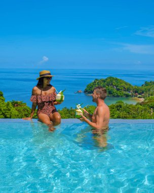 Tayland 'da sonsuzluk havuzunda bir çift Avrupalı erkek ve Asyalı kadın okyanusa bakıyor, Tayland' da lüks bir tatil.