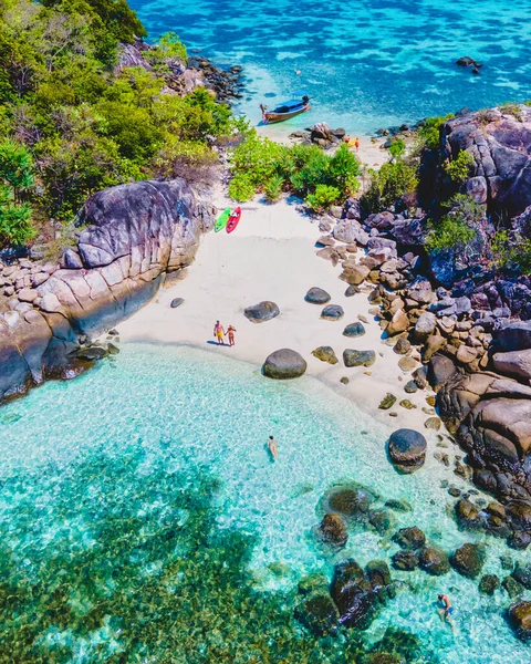 Güney Tayland 'da Koh Lipe Adası' nın önündeki Kla Adası sahilinde turkuaz renkli okyanusları ve güneşli bir günde Ko Lipe 'de kanosu olan beyaz kumlu plajları olan bir çift.