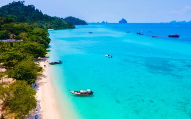 Tayland 'daki Koh Kradan adasının kumsalında insansız hava aracı görüntüsü güneşli bir günde okyanusta uzun kuyruklu teknelerle Koh Kradan Adası üzerinde hava manzarası.