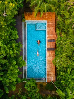 Krabi Tayland 'ın ormanında bir yüzme havuzunda iki erkek ve kadın. Tayland ormanında yüzme havuzunun üstünde bir dron..