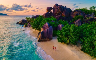 Anse Source dArgent beach, La Digue Island, Seyshelles, Drone aerial view of La Digue Seychelles bird eye view.of tropical Island, couple men and woman walking at the beach during sunset at a luxury