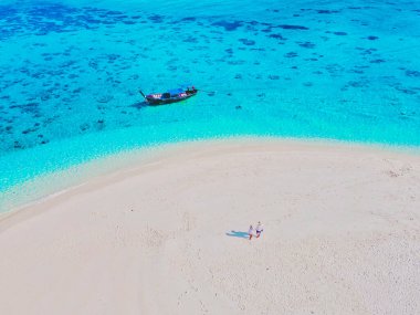 Koh Lipe Adası Güney Tayland 'daki beyaz bir kumsalda, turkuaz renkli okyanuslar ve güneşli bir günde Ko Lipe' de beyaz kumsallı bir kumsalda birkaç kadın ve erkek.