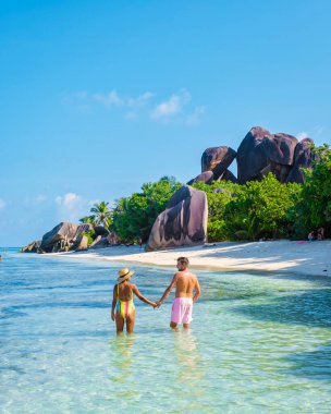 Anse Source dArgent, La Digue Seychelles, Seyşeller 'de lüks bir tatil sırasında tropikal bir plajda yaşayan genç bir çift. Tropik sahil Anse Kaynak dArgent, La Digue Seyşeller
