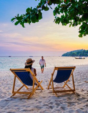 Gün batımında Koh Lipe Tayland sahilinde plaj sandalyesinde dinlenen çift, Tayland 'da tatilde olan erkekler ve kadınlar.