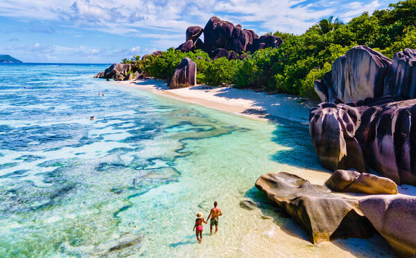 Anse Source dArgent beach, La Digue Island, Seyshelles, Drone aerial view of La Digue Seychelles bird eye view.of tropical Island, couple men and woman walking at the beach during sunset at a luxury