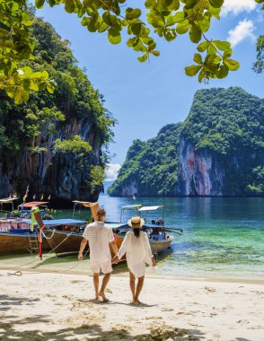 Tayland 'daki Koh Hong Adaları' nın bir parçası olan Koh Loa Lading Krabi Tayland 'ın Tropikal lagünündeki kadın ve erkekler. Kireçtaşı kayalıkları ve uzun kuyruklu tekneleri olan güzel bir sahil.