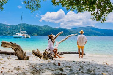 Koh Lipe Adası 'nın güney Tayland sahilinde turkuaz renkli okyanus ve Ko Lipe' deki beyaz kumlu plajda dinlenen bir kadın ve erkek. Tarutao Ulusal Parkı, Koh Rawi Adası