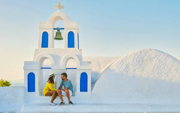 男性と女性の観光客の若いカップルは ホワイトウォッシュの家や教会 ギリシャ島のエーゲ海のキクラデスと夏の晴れた日にOia Santoriniギリシャを訪問します — ストック写真