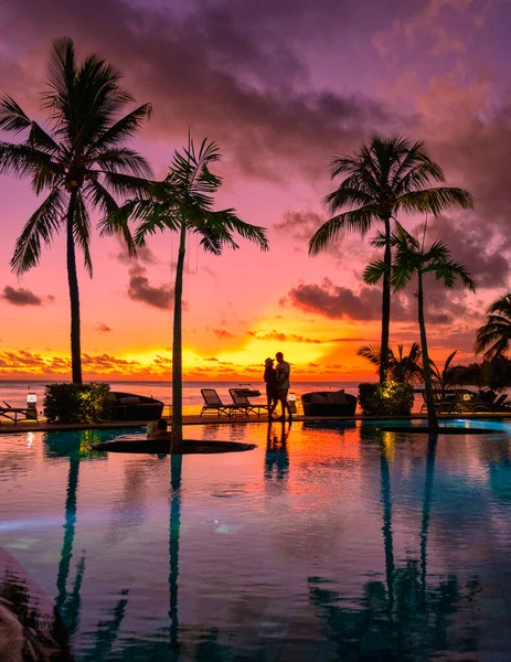 几个男人和女人在毛里求斯的一个热带海滩上观看日落 他们在游泳池边的棕榈树下观看日落 在毛里求斯的海滩上观看热带日落 — 图库照片