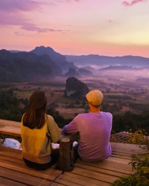 Kuzey Tayland 'daki Phu Langka Dağları' nda Phayao Eyaleti 'ndeki Phu Langka Ulusal Parkı' nın Dağ Manzarası 'nda gün doğumunu sis ve sisle izleyen iki erkek ve kadın.