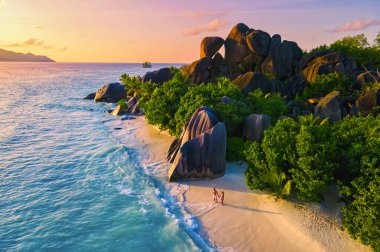 Anse Source dArgent, La Digue Seychelles, Seyşeller 'de lüks bir tatil sırasında tropikal bir plajda yaşayan genç bir çift. Tropik sahil Anse Kaynak dArgent, La Digue Seyşeller