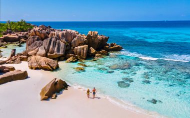 Anse Cocos plajı, La Digue Adası, Seyshelles, La Digue Seychelles 'in insansız hava görüntüsü. Tropik adanın kuş bakışı görüntüsü. Günbatımında plajda yürüyen birkaç erkek ve kadın.