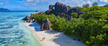 Anse Source dArgent, La Digue Seychelles, Seyşeller 'de lüks bir tatil sırasında tropikal bir plajda yaşayan genç bir çift. Tropik sahil Anse Kaynak dArgent, La Digue Seyşeller