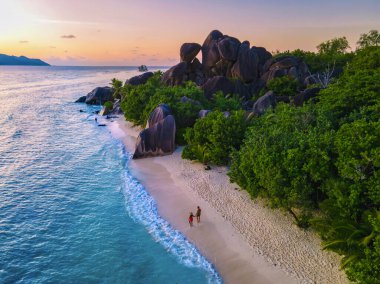 Anse Source dArgent, La Digue Seychelles, Seyşeller 'de lüks bir tatil sırasında tropikal bir plajda yaşayan genç bir çift. Tropik sahil Anse Kaynak dArgent, La Digue Seyşeller