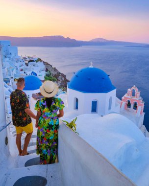 A couple walking at the village of Oia Santorini Greece, men and women visit the whitewashed Greek village of Oia during summer vacation