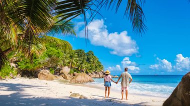 Anse Patates, La Digue Seychelles, a young couple of men and women on a tropical beach during a luxury vacation in Seychelles. Tropical beach Anse Patates, La Digue Seychelles