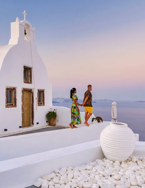 一对夫妇带着蓝色的圆顶和白色的教堂观赏着圣托里尼的日出 他们参观了粉刷一新的希腊村庄Oia Santorini — 图库照片