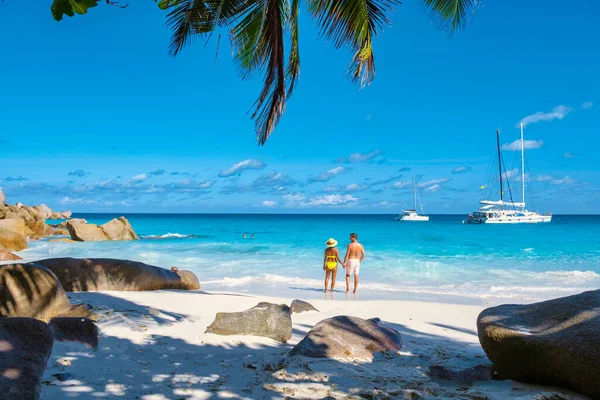 Anse Georgette Praslin Seychelles, young couple of men and woman on a tropical beach during a luxury vacation in Seychelles. Tropical beach Anse Georgette Praslin Seychelles.