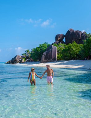 Anse Source dArgent, La Digue Seychelles, Seyşeller 'de lüks bir tatil sırasında tropikal bir plajda yaşayan genç bir çift. Tropik sahil Anse Kaynak dArgent, La Digue Seyşeller