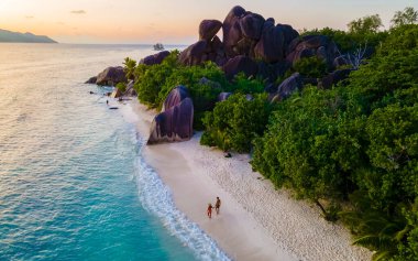 Anse Source dArgent, La Digue Seychelles, Seyşeller 'de lüks bir tatil sırasında tropikal bir plajda yaşayan genç bir çift. Tropik sahil Anse Kaynak dArgent, La Digue Seyşeller