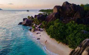 Anse Source dArgent, La Digue Seychelles, Seyşeller 'de lüks bir tatil sırasında tropik bir plajda iki genç erkek ve kadın.. 