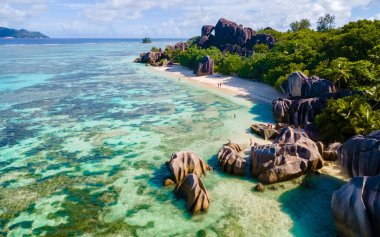 Anse Source dArgent, La Digue Seychelles, Seyşeller 'de lüks bir tatil sırasında tropik bir plajda iki genç erkek ve kadın.. 