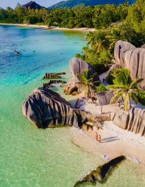 Anse Source dArgent, La Digue Seychelles, gün batımında tropik bir plajda genç bir çift kadın ve erkek, insansız hava aracı görüntüsü.