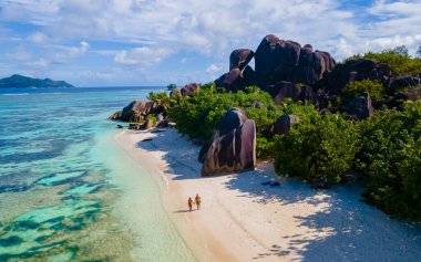 Anse Source dArgent, La Digue Seychelles, gün batımında tropik bir plajda genç bir çift kadın ve erkek, insansız hava aracı görüntüsü.