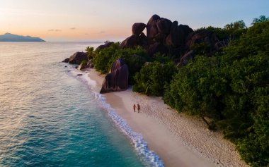 Anse Source dArgent, La Digue Seychelles, gün batımında tropik bir plajda genç bir çift kadın ve erkek, insansız hava aracı görüntüsü.