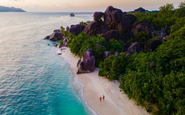 Anse Source dArgent, La Digue Seychelles, gün batımında tropik bir plajda genç bir çift kadın ve erkek, insansız hava aracı görüntüsü.