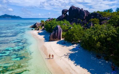 Anse Source dArgent, La Digue Seychelles, Seyşeller 'de lüks bir tatil sırasında tropik bir plajda iki genç erkek ve kadın.. 