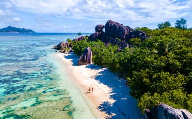 Anse Source dArgent, La Digue Seychelles, Seyşeller 'de lüks bir tatil sırasında tropikal bir plajda yaşayan genç bir çift. Tropik sahil Anse Kaynak dArgent, La Digue Seyşeller