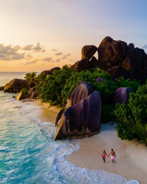 Anse Source dArgent, La Digue Seychelles, Seyşeller 'de lüks bir tatil sırasında tropikal bir plajda yaşayan genç bir çift. Tropikal bir plajın yukarısından drone görüntüsü