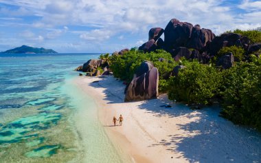Anse Source dArgent, La Digue Seychelles, Seyşeller 'de lüks bir tatil sırasında tropikal bir plajda yaşayan genç bir çift. Tropikal bir plajın yukarısından drone görüntüsü