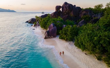 Anse Source dArgent, La Digue Seychelles, Seyşeller 'de lüks bir tatil sırasında tropikal bir plajda yaşayan genç bir çift. Tropikal bir plajın yukarısından drone görüntüsü