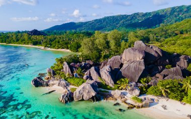Anse Source dArgent, La Digue Seychelles, Seyşeller 'de lüks bir tatil sırasında tropikal bir plajda yaşayan genç bir çift. Tropik sahil Anse Kaynak dArgent, La Digue Seyşeller