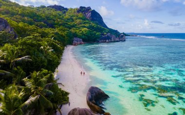 Anse Source dArgent, La Digue Seyşeller, tropikal bir plajda genç bir çift kadın ve erkek, Seyşeller Adaları 'ndaki tropik bir plajın insansız hava aracı görüntüsü.