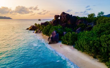 Seyşeller 'de lüks bir tatil sırasında, Anse Source dArgent, La Digue Seychelles, tropikal bir plajda genç bir çift kadın ve erkek drone görüntüsü. Tropik sahil Anse Kaynak dArgent, La