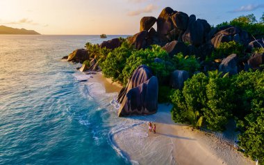 Anse Source dArgent, La Digue Seychelles, Seyşeller 'de lüks bir tatil sırasında tropikal bir plajda yaşayan genç bir çift. Tropik sahil Anse Kaynak dArgent, La Digue Seyşeller