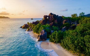 Anse Source dArgent, La Digue Seychelles, Seyşeller 'de lüks bir tatil sırasında tropikal bir plajda yaşayan genç bir çift. Tropik sahil Anse Kaynak dArgent, La Digue Seyşeller