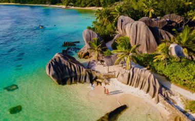 Anse Source dArgent, La Digue Seychelles, Seyşeller 'de lüks bir tatil sırasında tropikal bir plajda yaşayan genç bir çift. Tropikal bir plajın yukarısından drone görüntüsü