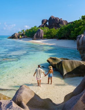 Seyşeller 'de lüks bir tatil sırasında tropikal bir plajda bulunan genç bir çift. Tropik sahil Anse Kaynak dArgent, La Digue Seyşeller